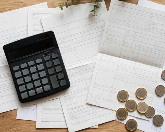 Calculator, UK tax documents and British pound coins on a desk